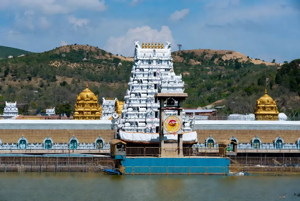 Tirupati Venkateswara Temple in Andhra Pradesh, with its golden shikhara gleaming in the sunlight and the surrounding hills.